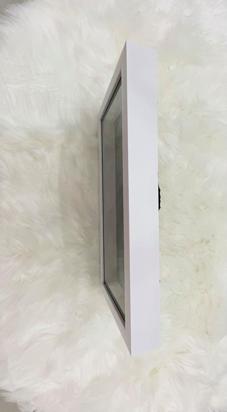 May include: White shadow box with a clear glass front. The shadow box is empty.