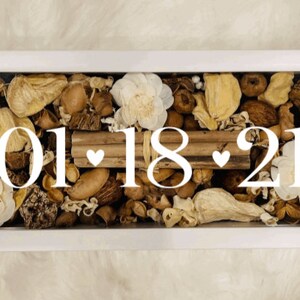 May include: A white frame filled with dried flowers, leaves, and pods. The date "01.18.21" is written in white lettering with two small hearts.