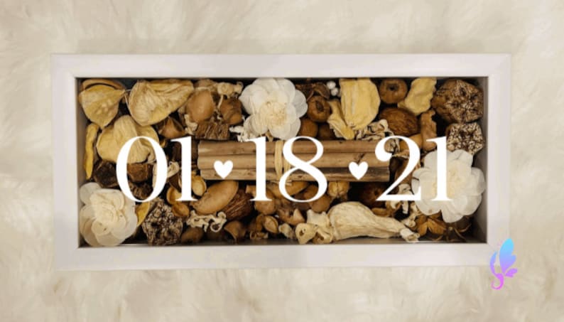 May include: A white frame filled with dried flowers, leaves, and pods. The date "01.18.21" is written in white lettering with two small hearts.