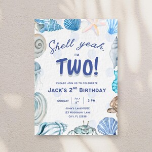 May include: A rectangular birthday invitation card featuring watercolor illustrations of blue and tan seashells, a starfish, and a crab. The text reads: Shell yeah, I'M TWO! PLEASE JOIN US TO CELEBRATE JACK'S 2ND BIRTHDAY, SUNDAY JULY 8TH 3 PM, JOHN'S LAKEHOUSE 123 WOODBURY LANE CITY, FL 12938.