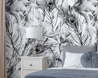 May include: A white bed with a gray knitted blanket and a gray headboard. The wall behind the bed has a black and white floral wallpaper with a peacock feather design.