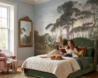 May include: A bedroom featuring a large green upholstered bed with a cream quilted coverlet, a person reading a book, and two cats resting on the bed. The wall behind the bed displays a large landscape mural of trees under a soft sky.