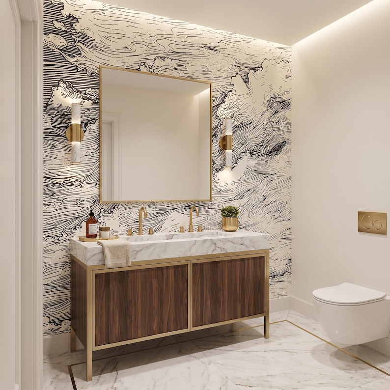 May include: A bathroom vanity featuring a white marble countertop with two gold faucets, a dark wood cabinet with gold trim, and a square mirror. The wall behind the vanity is covered in black and white wallpaper with a swirling wave pattern.