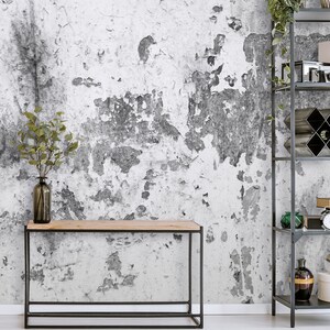 Puede incluir: Una mesa consola de metal negro con una tapa de madera se encuentra frente a una pared blanca con un acabado texturizado y desgastado. Un jarr&oacute;n con ramas verdes se encuentra sobre la mesa.