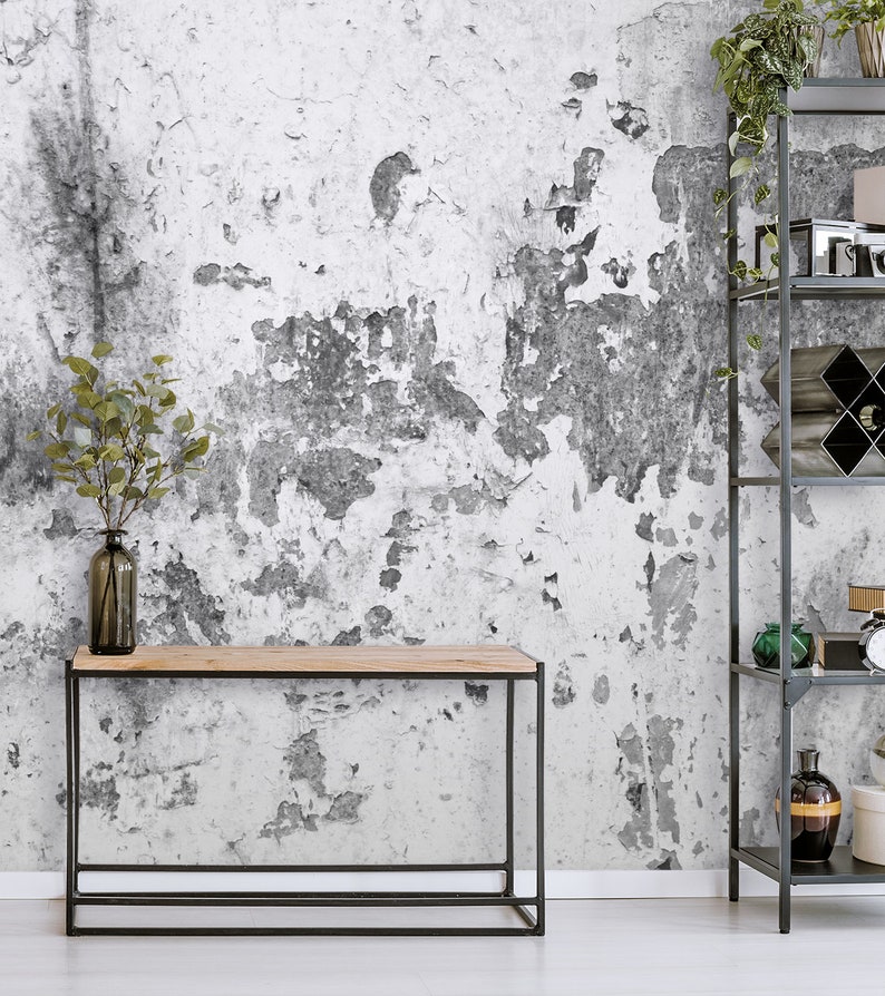 Puede incluir: Una mesa consola de metal negro con una tapa de madera se encuentra frente a una pared blanca con un acabado texturizado y desgastado. Un jarr&oacute;n con ramas verdes se encuentra sobre la mesa.