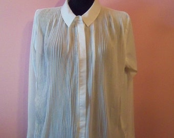 May include: A white, long-sleeved, button-up shirt with a pleated front and a ruffled hem.