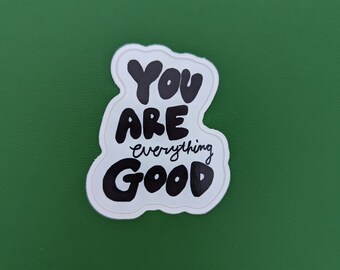 May include: A white sticker with a black outline and the words "YOU ARE everything GOOD" in a bold, handwritten font. The sticker is on a green background.