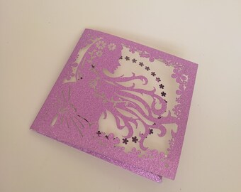 May include: A purple glitter card with a cut-out design of a woman's silhouette with floral accents.