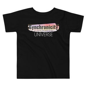 Op de afbeelding: Zwart T-shirt voor peuters met een kleurrijk abstract ontwerp en de tekst "Synchronicity A wink from the UNIVERSE" in wit.
