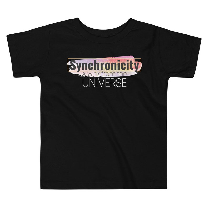 Op de afbeelding: Zwart T-shirt voor peuters met een kleurrijk abstract ontwerp en de tekst "Synchronicity A wink from the UNIVERSE" in wit.