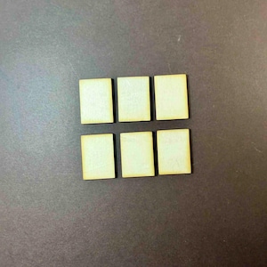 May include: Six small, square wooden tiles arranged in two rows of three. The tiles have a light, natural wood color with a slightly darker edge. The background is a dark, solid color.