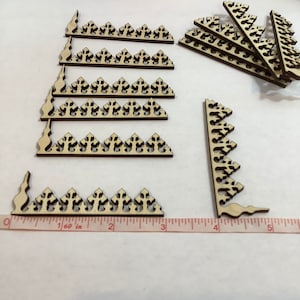 May include: A set of 10 wooden decorative trim pieces with a repeating pattern of pointed arches. The trim pieces are approximately 3 inches long and are made of light brown wood.