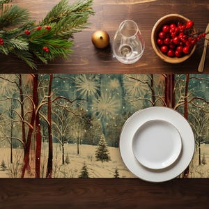 Puede incluir: Una mesa festiva con un camino de mesa con tema de bosque invernal, platos blancos con bordes dorados y elementos decorativos. Incluye un cuenco de bayas rojas, una jarra de cristal y un adorno dorado. La mesa está sobre una superficie de madera oscura.
