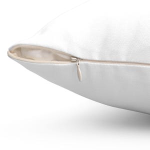 May include: A white pillow with a zipper closure. The zipper is visible and the zipper pull is silver.