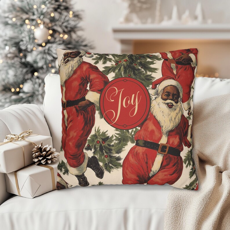 Pu&ograve; includere: Un cuscino bianco con un motivo natalizio festoso con Babbo Natale neri in costume rosso e rami di agrifoglio verdi. Il cuscino ha un cerchio rosso con la parola "Joy" in caratteri bianchi.