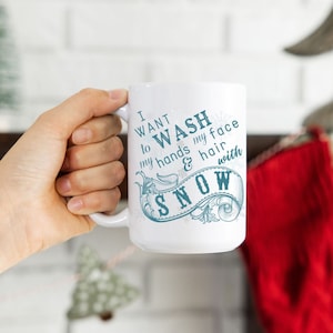 May include: White ceramic mug with a blue and white design that says "I want to wash my hands & hair with snow".