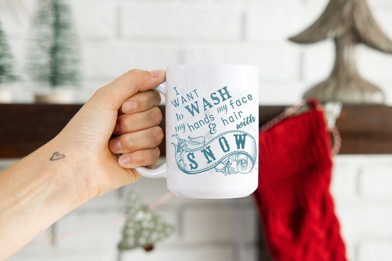 May include: White ceramic mug with a blue and white design that says "I want to wash my hands & hair with snow".
