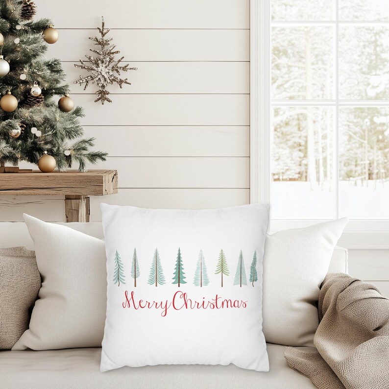May include: White throw pillow with a red "Merry Christmas" message and a row of green and blue stylized Christmas trees.