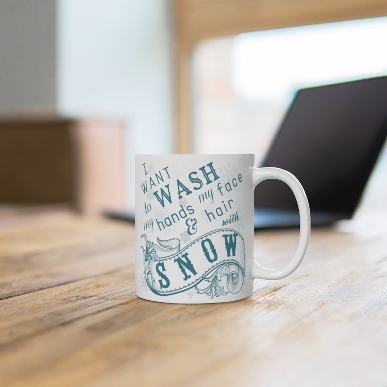 May include: White ceramic mug with a blue design that says "I want to wash my hands & hair with snow".