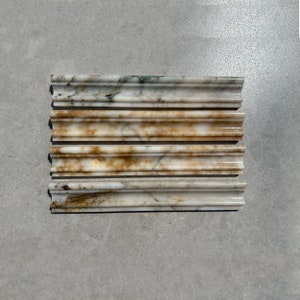 May include: Five pieces of white marble trim with brown and gold veining. The trim has a decorative, raised edge.
