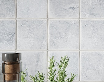 May include: A close-up of a gray tiled wall with a sprig of rosemary in front of it. A clear glass bottle with a cork stopper is also in the image.