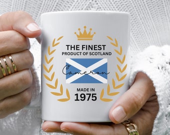 May include: White ceramic mug with a gold crown, laurel wreath, and the text "The Finest Product of Scotland" with the Scottish flag and the name "Cameron" written in cursive. The text "Made in 1975" is also printed on the mug.