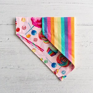 Könnte beinhalten: Ein rosa und regenbogenfarbenes Bandana mit einem Bonbon- und Cupcake-Druck. Das Bandana ist dreieckig gefaltet.