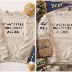 May include: Cream-colored sweatshirt with "NC A&T State University Aggies" printed in navy blue. The left sleeve reads "NCAT MADE" in blue. A yellow baseball cap with "NCAT" is also visible, along with other university-themed items.