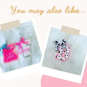 May include: Two personalized car air fresheners, one pink with glitter and the word "Lilis" and the other white with glitter and the word "Freshsies". Both have pink bows.