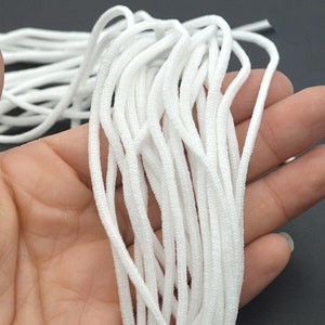 May include: A close-up of a bundle of white elastic cord, commonly used for face masks or other crafts.