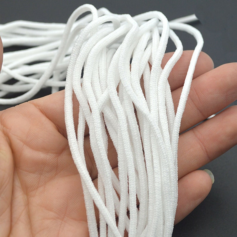 May include: A close-up of a bundle of white elastic cord, commonly used for face masks or other crafts.