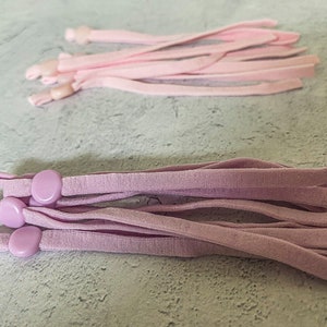 May include: A bundle of light purple elastic cords with plastic slider toggles. The cords are approximately 10 inches long.
