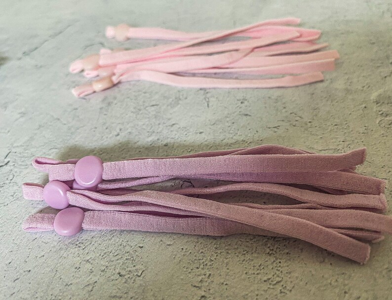 May include: A bundle of light purple elastic cords with plastic slider toggles. The cords are approximately 10 inches long.