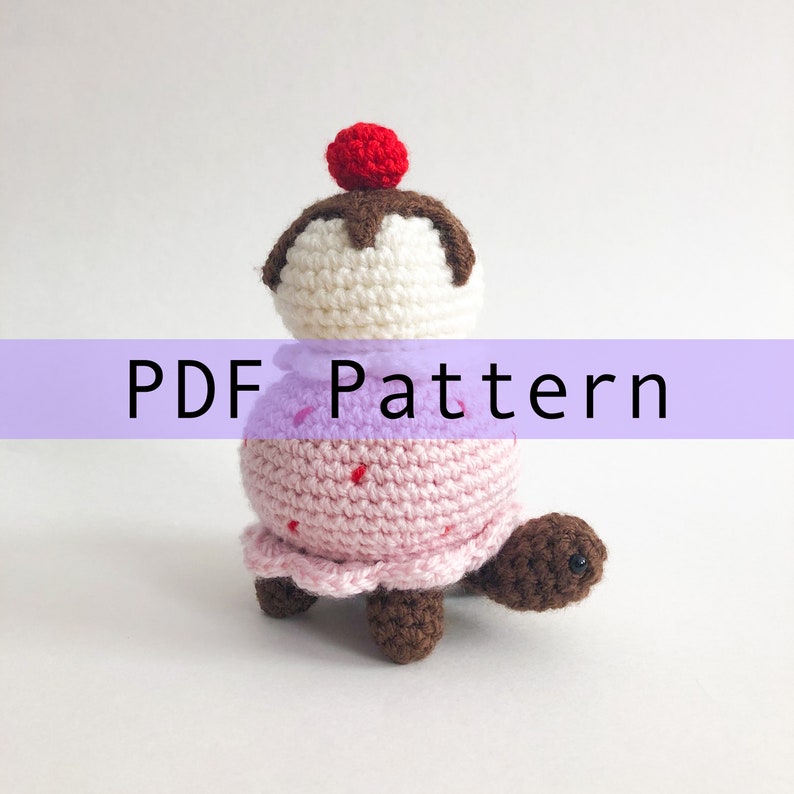 May include: Crochet pattern for a pink and white ice cream cone turtle amigurumi. The pattern is available as a PDF download.