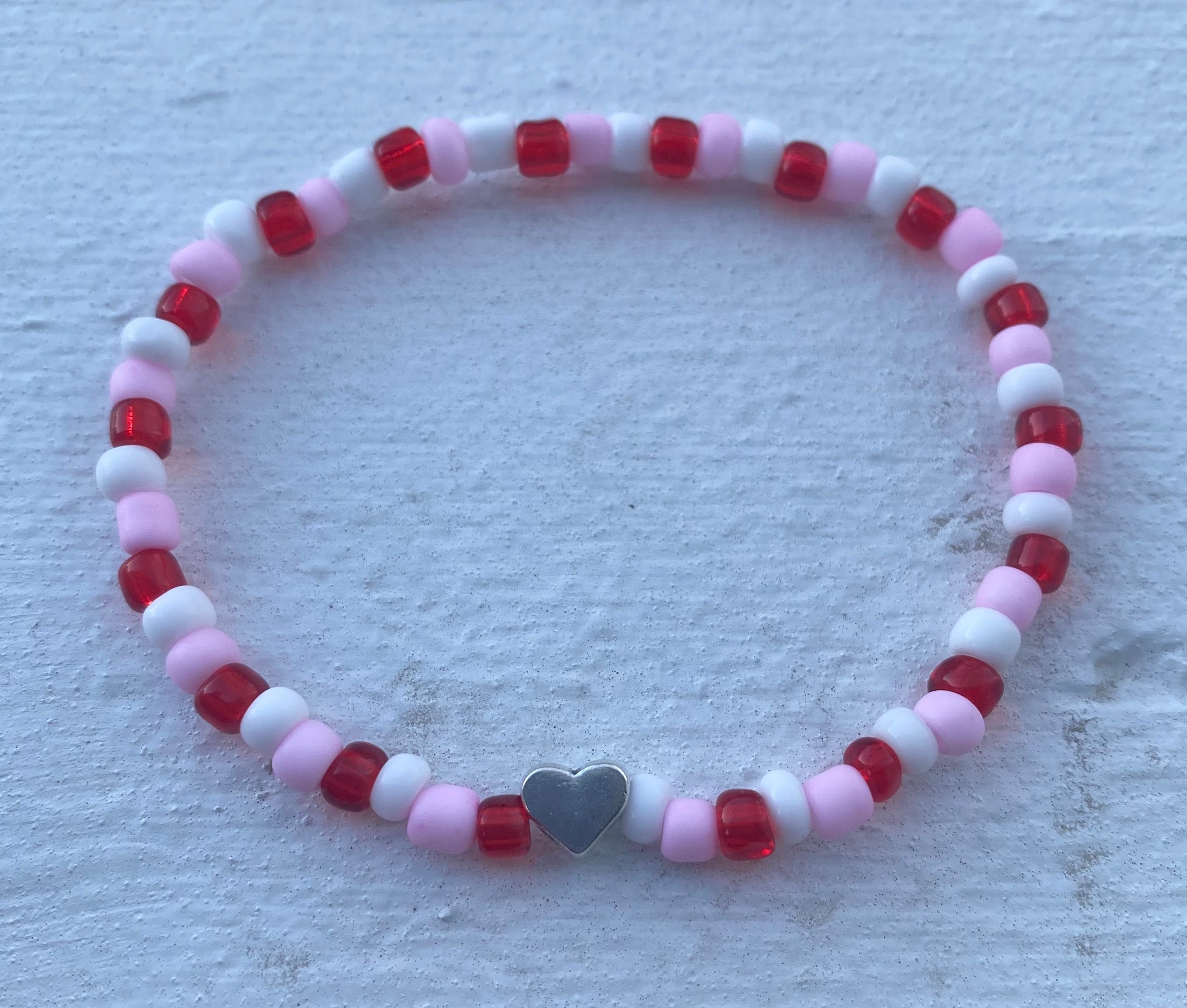 Pink string with pink red blue hearts beads on white background