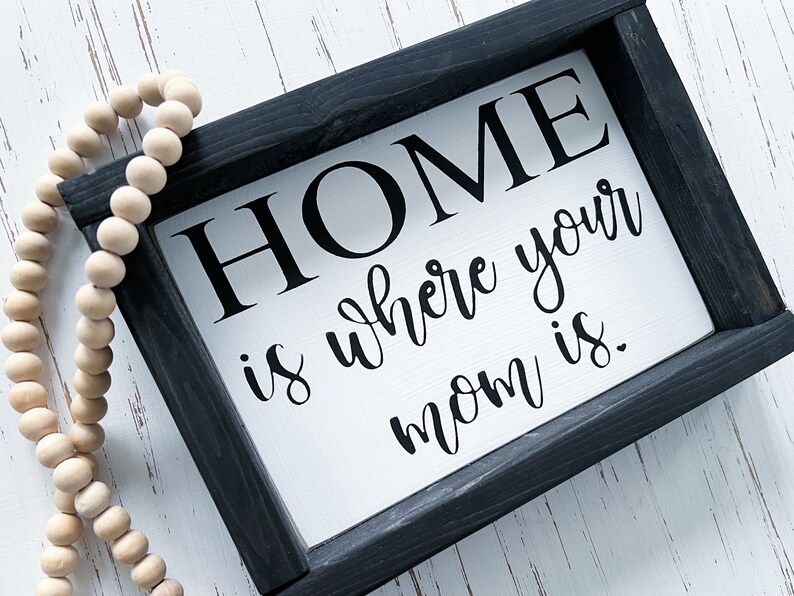 May include: Black framed sign with white background and the text "HOME is where your mom is."