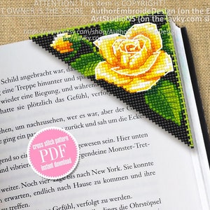 May include: A yellow rose cross stitch pattern bookmark with green leaves on a black background. The bookmark is on top of an open book. The text on the bookmark says "cross stitch pattern PDF instant download".