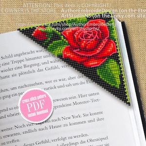 May include: A cross stitch pattern for a bookmark featuring a red rose with green leaves on a black background. The pattern is available as a PDF instant download. The text "cross stitch pattern PDF instant download" is on a pink circle.