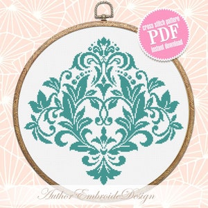 May include: A teal blue cross stitch pattern of a damask design in a wooden embroidery hoop. The pattern is available as a PDF instant download. The text "cross stitch pattern PDF instant download" is on a pink circle.