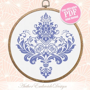 May include: A purple and white cross stitch pattern of a damask design in a round embroidery hoop. The pattern is available as a PDF instant download. The text "cross stitch pattern PDF instant download" is on a white circle with a pink border.