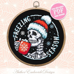 Op de afbeelding: PDF-patroon voor kruissteek van een skelet met een kerstmanmuts en een rode mok met een sneeuwvlok. De tekst rond het skelet luidt "Freezing Season".