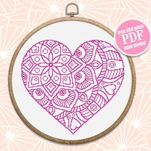 May include: A pink and white cross stitch pattern of a heart with intricate designs. The pattern is in a wooden embroidery hoop. The text "cross stitch pattern PDF instant download" is on a pink circle.