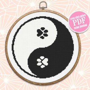 May include: Black and white cross stitch pattern of a yin yang symbol with paw prints in each half. The pattern is in a wooden embroidery hoop. The text "cross stitch pattern PDF instant download" is on a pink starburst.