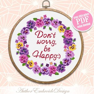 May include: Cross stitch pattern PDF download featuring a wreath of purple, yellow, and pink pansies with the text "Don't worry, be Happy".
