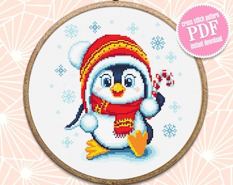 May include: Cross stitch pattern PDF instant download of a cute penguin wearing a red hat and scarf with a candy cane in its hand. The penguin is surrounded by snowflakes on a white background.