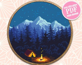May include: Cross stitch pattern PDF for a night scene with a campfire, tent, and mountains in the distance. The sky is dark blue with white stars. The mountains are blue and white. The trees are dark green. The campfire is orange and yellow. The tent is red and orange.