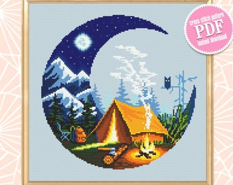 Peut inclure: Modèle de point de croix PDF à télécharger instantanément représentant une lune croissante avec une scène de camping à l'intérieur. La scène comprend une tente, un feu de camp, des montagnes, des arbres et un chat noir.