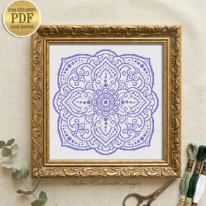 Pode incluir: Um padrão de ponto cruz emoldurado com um design de mandala lavanda. A moldura dourada envolve a obra de arte, com fios de bordar e tesouras visíveis. O texto "cross stitch pattern PDF instant download" está no canto superior esquerdo.