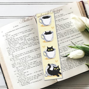 Puede incluir: Un marcap&aacute;ginas con fondo amarillo y un gato negro asom&aacute;ndose a una taza de t&eacute;. El marcap&aacute;ginas tiene cuatro im&aacute;genes de gatos en tazas de t&eacute;, cada uno con una postura diferente. El texto "Author Embroide Design" est&aacute; impreso en el marcap&aacute;ginas.