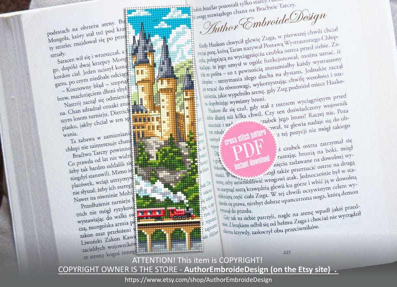 Puede incluir: Un marcap&aacute;ginas de punto de cruz con un castillo y un tren, sobre un cielo azul con nubes. El marcap&aacute;ginas est&aacute; en un libro abierto. El texto en el marcap&aacute;ginas dice "Author Embroide Design".